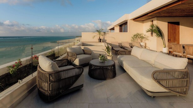 A rooftop terrace with wicker furniture, a round table, and potted plants. - Oceanfront Escape – Two-Level Penthouse with Private Rooftop & Pool (Tulum)