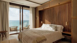 A bedroom with a large bed, a view of the ocean, and a balcony with chairs. - Oceanfront Escape – Two-Level Penthouse with Private Rooftop & Pool (Tulum)