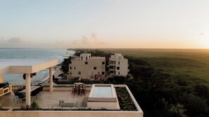 Un hotel moderno con piscina sul tetto, area salotto all'aperto e vista sull'oceano.