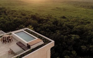 A rooftop terrace with a rectangular pool, wooden furniture, and a view of a dense forest. - Oceanfront Escape – Two-Level Penthouse with Private Rooftop & Pool (Tulum)