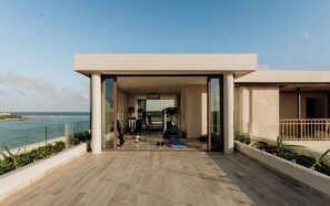 Area moderna di palestra all'aperto con attrezzature, vista sull'oceano e ringhiera in vetro.