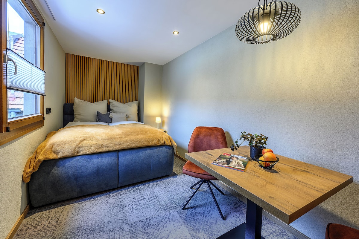 A modern bedroom with a bed, a dining table, and a chair.
