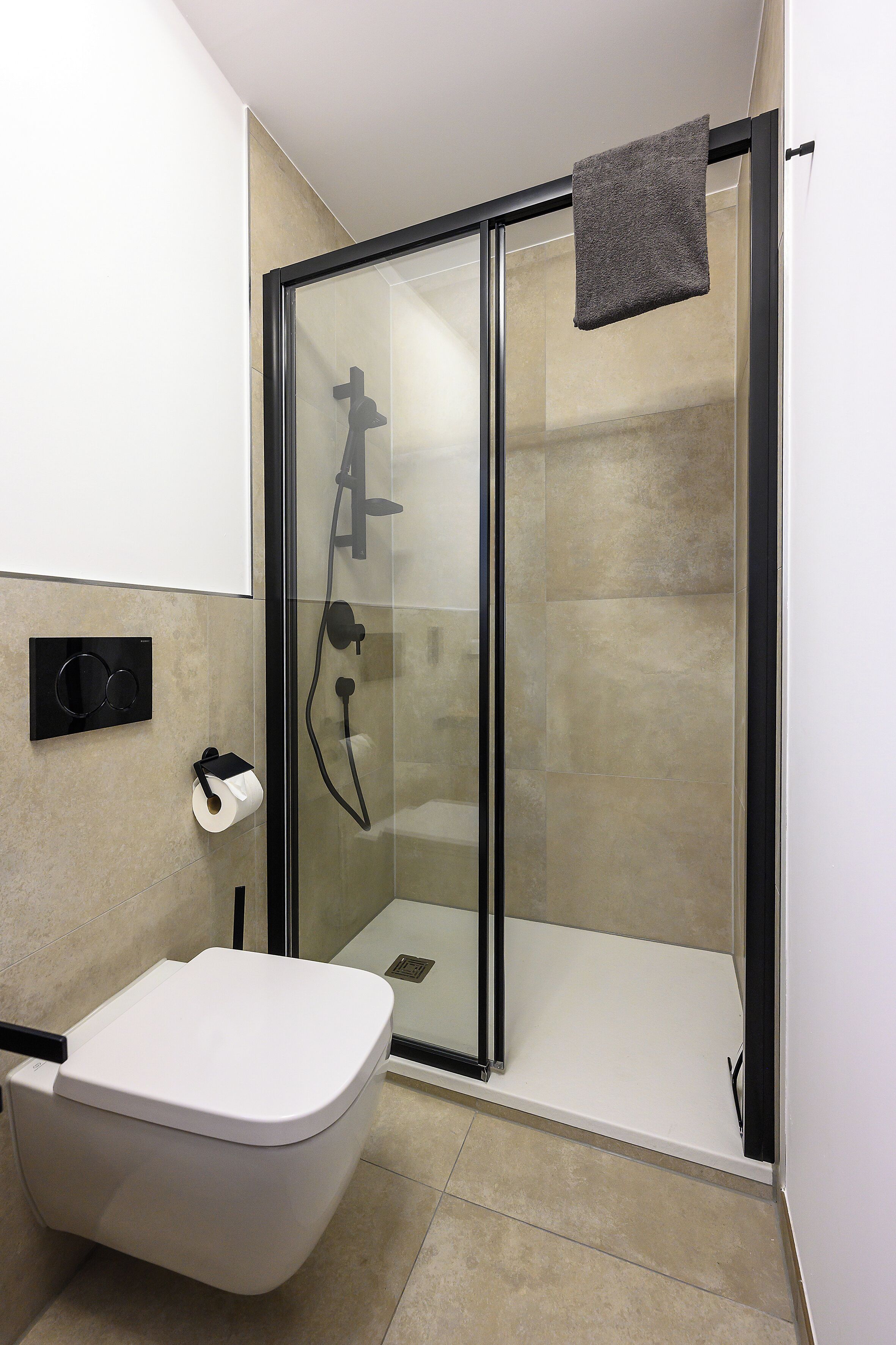Ein modernes Badezimmer mit einer Duschkabine, einer Toilette und einem Handtuch an der Duschkabinentür.