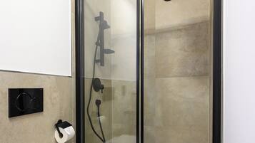 Ein modernes Badezimmer mit einer Duschkabine, einer Toilette und einem Handtuch an der Duschkabinentür.