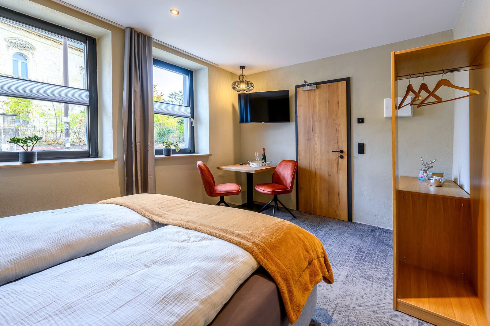 Ein Hotelzimmer mit einem Bett, einem Schreibtisch, zwei Stühlen, einem Fernseher und einem Kleiderschrank.