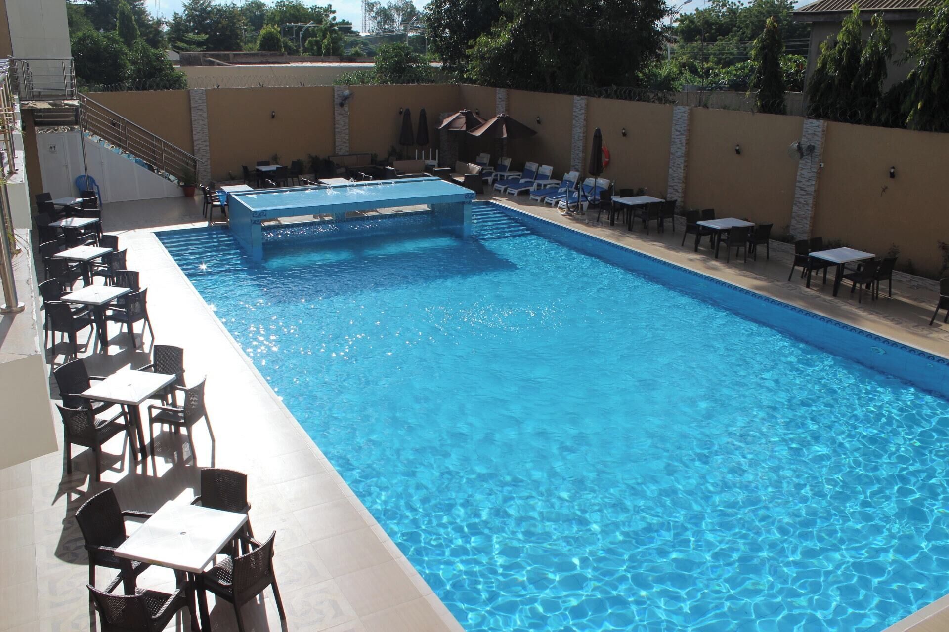 A swimming pool with lounge chairs and tables around it.
