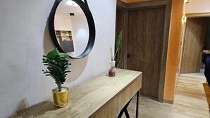 A wooden console table with a mirror, a potted plant, and a vase with a candle. - MTown Hotel and Suites  (Dutse)