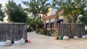 A gated entrance with a wooden fence, a staircase leading to a building, and a paved area with rocks and traffic cones. - MTown Hotel and Suites  (Dutse)
