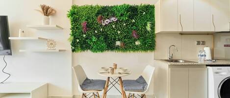 A modern kitchen with a green wall decor, a dining area with two chairs, and a washing machine.