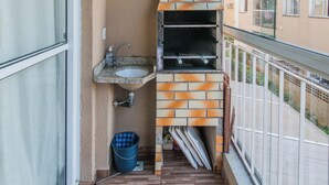 En balkon med indbygget murstensovn, vask og blå balje.