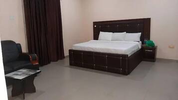 Un dormitorio con una cama grande, una mesita de noche, una silla y una mesa.