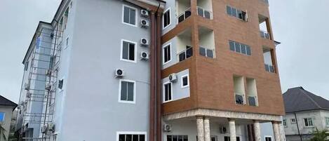 A multi-story residential building with a grey facade and a brown upper section.