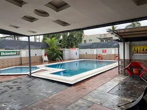 An outdoor swimming pool area with a Heineken sign, a lifeguard chair, and a safety sign. - AKMAG HOTELS  (Uyo)