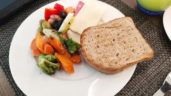 A plate with a slice of bread, mixed vegetables, and a piece of cheese.