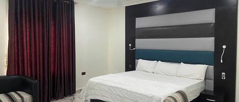 Un dormitorio moderno con una cama, una silla y una mesita de noche.