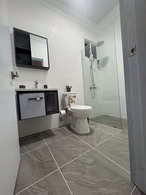 A modern bathroom with a toilet, sink, and shower. - Cozy 2-bedroom apartment in serene Bonao Dominican Republic with AC (Bonao)