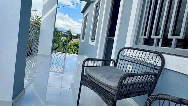 Un balcon avec une chaise et une table, un ciel dégagé et une vue sur la verdure.