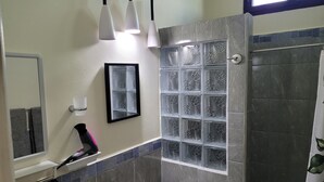 A bathroom with a toilet, a towel rack, a hairdryer, a mirror, and a window with decorative glass panels. - Luxury posada inn (Los Amates)