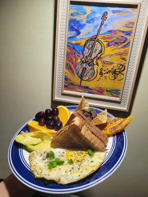 Ein Teller mit einem Ei, Avocado, Trauben, einer Orangenscheibe und einer Toastscheibe.