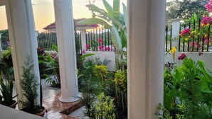 A garden with potted plants and flowers, surrounded by white columns and a tiled floor. - Luxury posada inn (Los Amates)