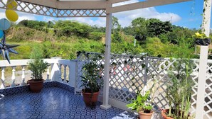 A covered patio with a tiled floor, white lattice railing, and potted plants. - Luxury posada inn (Los Amates)