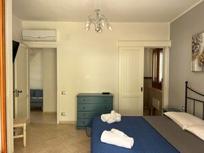 A bedroom with a bed, a dresser, a chandelier, and an air conditioning unit. - Stunning Ocean Views in Macari - Apartment, Grill, and Air Conditioning (Macari)