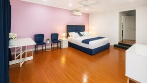 A bedroom with a bed, bedside tables, a desk, chairs, and a ceiling fan. - Luxury room + Pool + Ensuite (Bradbury)