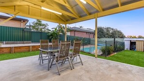 An outdoor patio with a covered seating area, a pool, and a fenced backyard. - Luxury room + Pool + Ensuite (Bradbury)