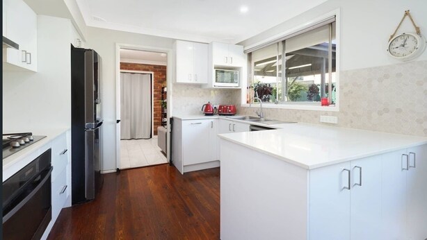 A modern kitchen with white cabinetry, a built-in microwave, and a window with a view of the outdoors. - Luxury room + Pool + Ensuite (Bradbury)