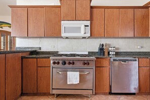 A kitchen with wooden cabinets, a stainless steel dishwasher, a built-in oven, and a microwave above the stove.
