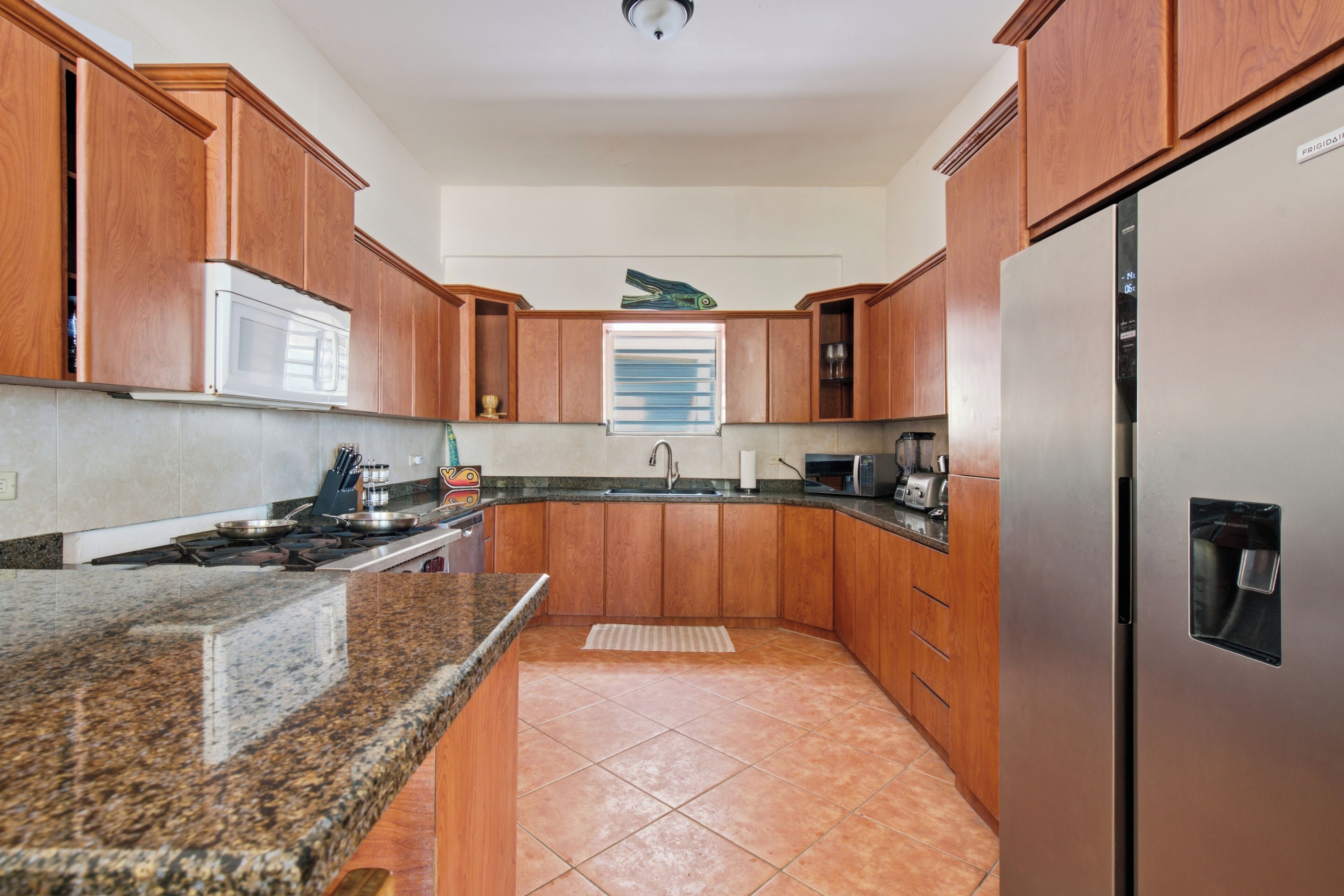 A kitchen with wooden cabinets, a stainless steel refrigerator, a microwave, and a gas stove.