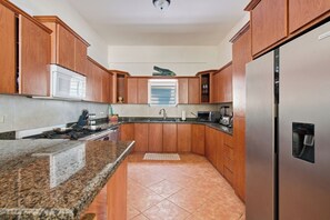 A kitchen with wooden cabinets, a stainless steel refrigerator, a microwave, and a gas stove.