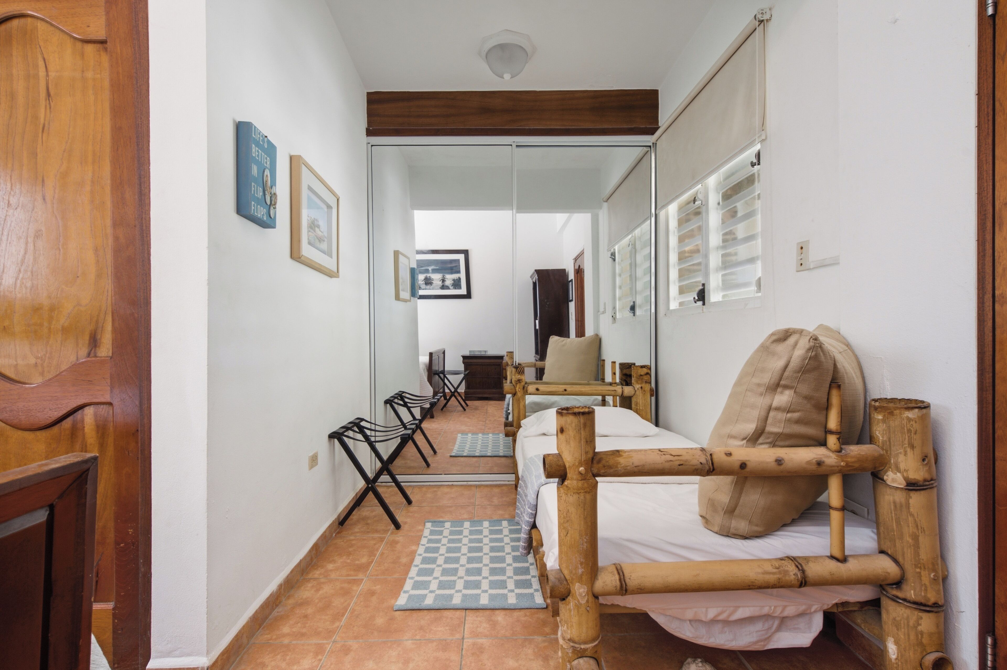 A narrow hallway with a bed, chairs, and a checkered mat.