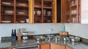 A kitchen with wooden cabinets, a granite countertop, and stainless steel cookware. - Eco friendly beachfront oasis (Rincón)