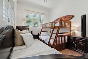 A room with a bunk bed, a desk, a chair, a lamp, and a television.
