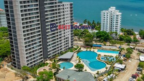 Un hôtel de grande hauteur doté de nombreux balcons, d’un espace piscine comprenant trois piscines et offrant une vue sur la mer.
