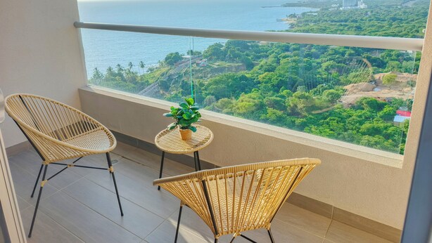 Un balcon avec des fauteuils en osier, une petite table et une plante en pot.