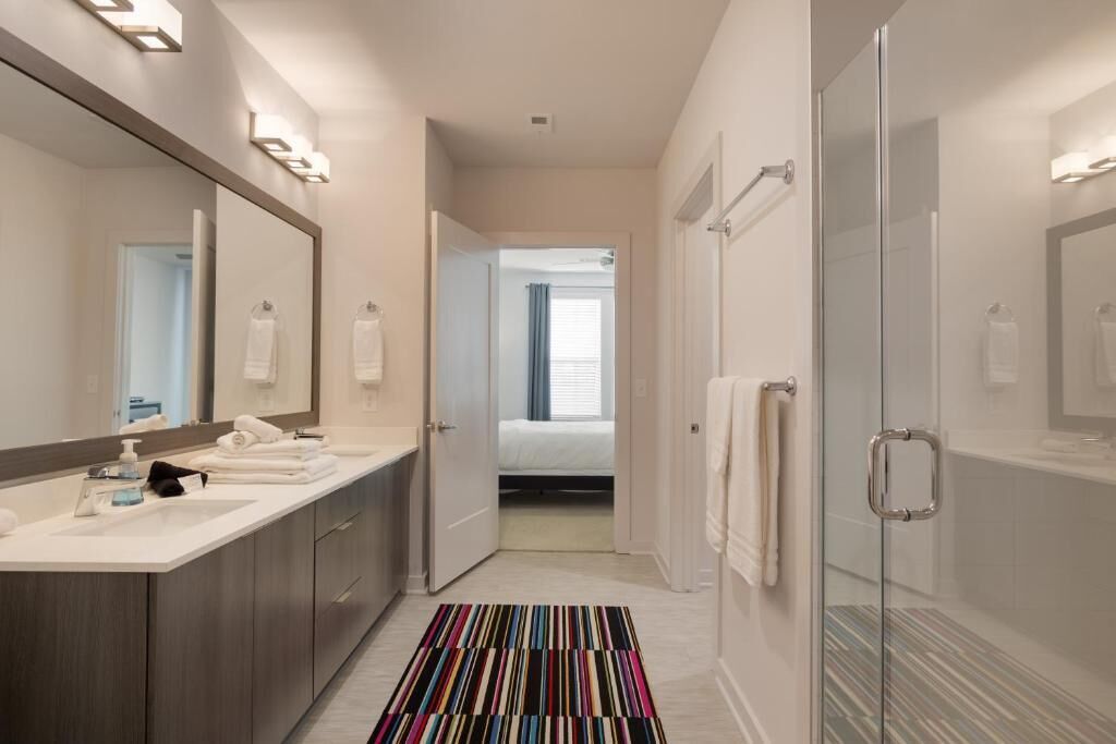 A modern bathroom with a large mirror, dual sinks, and a shower area.