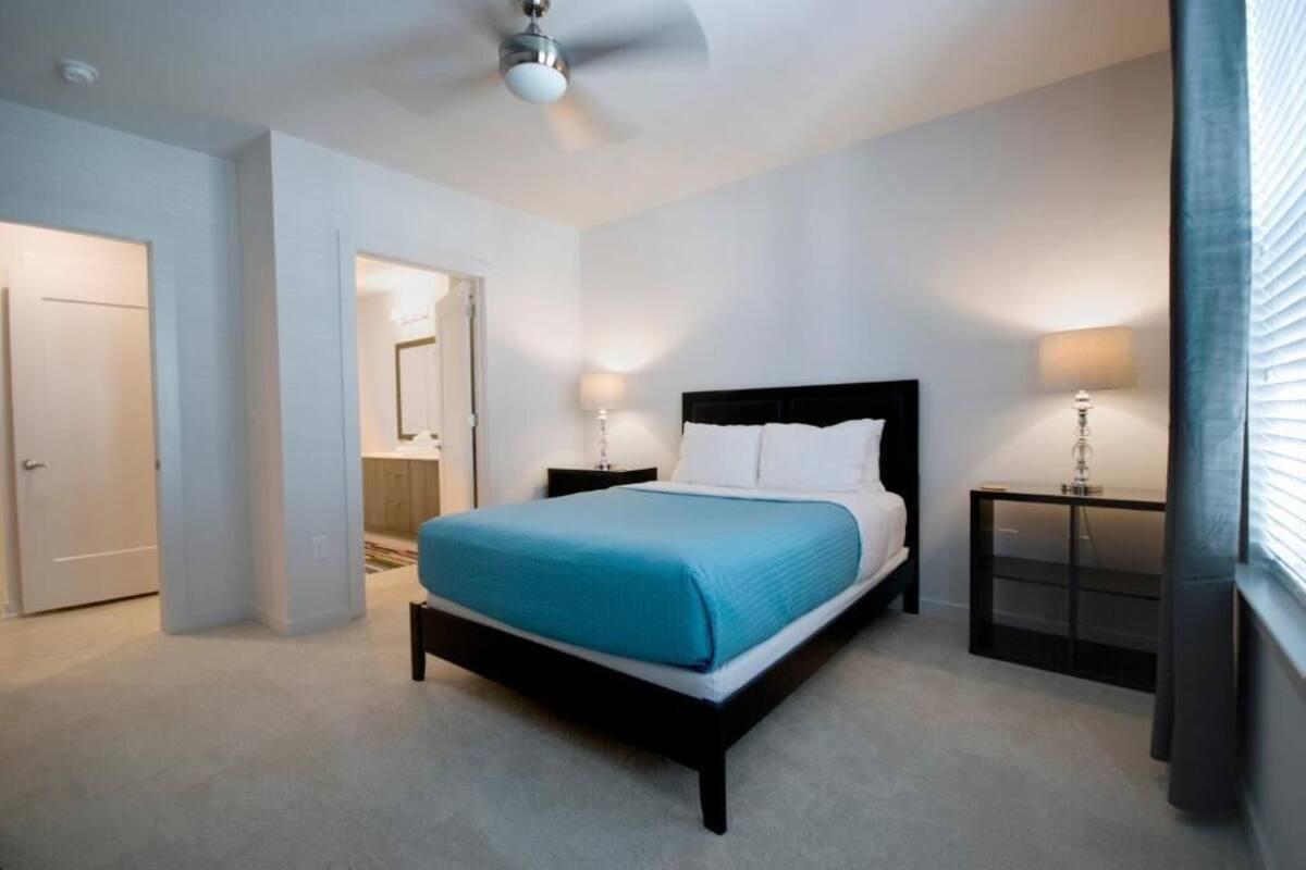 A bedroom with a bed, two bedside tables, a ceiling fan, and a door.