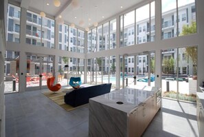 Een ruim, modern interieur met grote ramen, een marmeren eiland en een zwembad buiten.