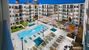 A modern building with multiple balconies and a central courtyard featuring a swimming pool and lounge areas. - BCA Spectacular Apartments (Atlanta)