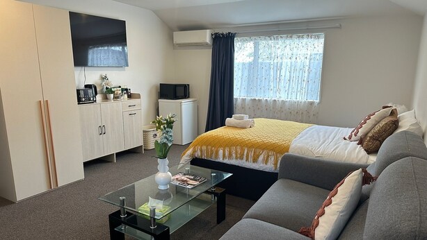 A modern hotel room with a bed, sofa, and a glass coffee table. - Comfort stay Christchurch (Christchurch)