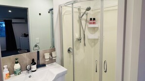 A modern bathroom with a glass-enclosed shower, a white sink with a marble countertop, and a large mirror. - Comfort stay Christchurch (Christchurch)