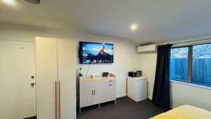 A hotel room with a bed, a TV mounted on the wall, a small kitchenette, and a window with curtains. - Comfort stay Christchurch (Christchurch)