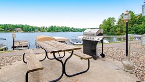 Picnicområde ved søen med grill, borde og liggestole.