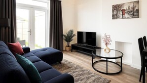 Un soggiorno moderno con divano, televisore e un quadro appeso al muro.