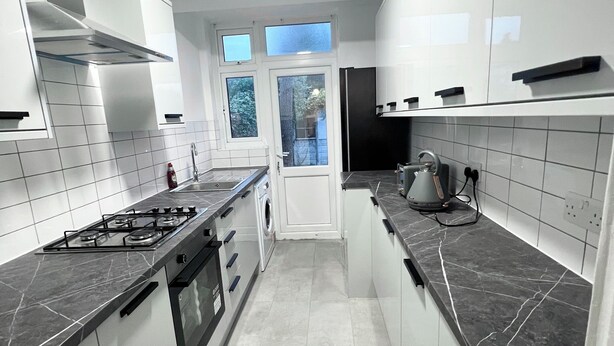 Una cucina moderna con mobili bianchi, un fornello a gas, forno integrato e macchina per il caffè.