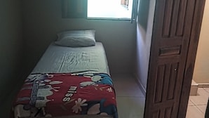Una habitación pequeña con una cama individual, una ventana y una puerta de madera.