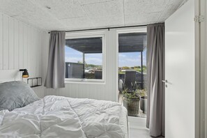 Een slaapkamer met een bed, een raam en uitzicht op de omgeving.
