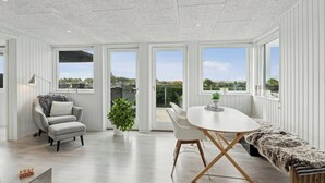 Ein modernes Interieur mit Esstisch, Stühlen, einer Bank, einer Couch und einer Topfpflanze.